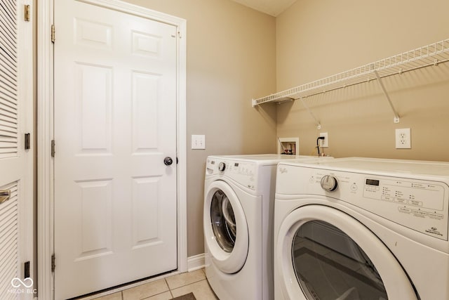 laundry area featuring washer and clothes dryer, laundry area, baseboards, and light tile patterned floors