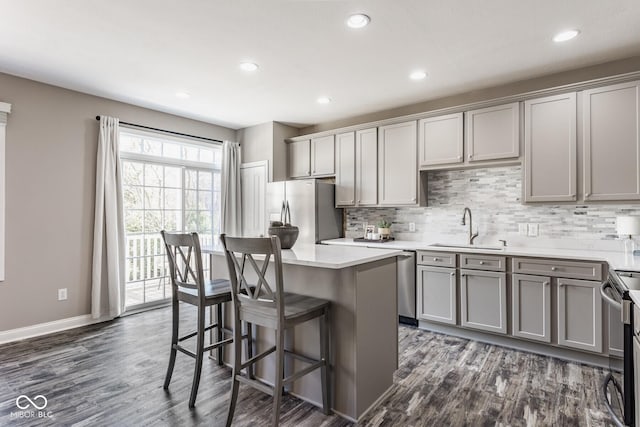 kitchen with a sink, decorative backsplash, gray cabinetry, and appliances with stainless steel finishes