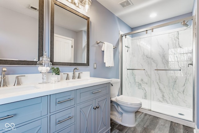 bathroom with wood finished floors, visible vents, a marble finish shower, a sink, and toilet