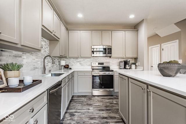 kitchen featuring gray cabinets, a sink, stainless steel appliances, light countertops, and backsplash