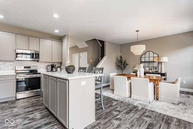 kitchen featuring a breakfast bar, dark wood-style floors, gray cabinets, and stainless steel appliances