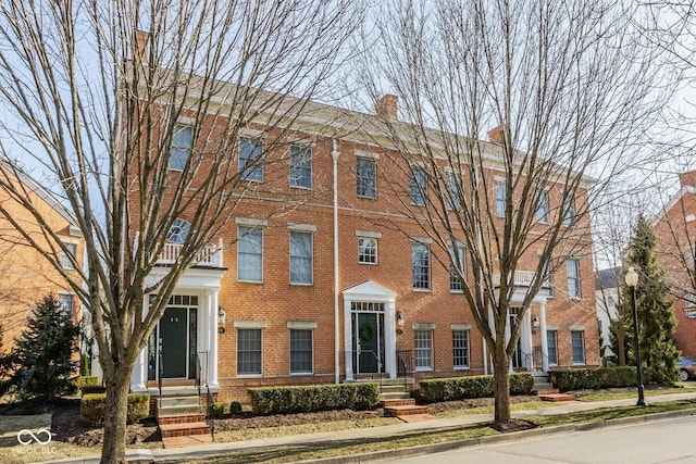 view of front of home with brick siding and a chimney