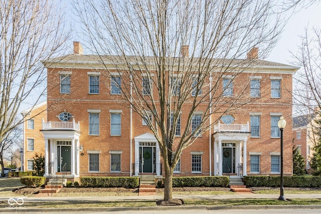 view of front of home with brick siding and a chimney