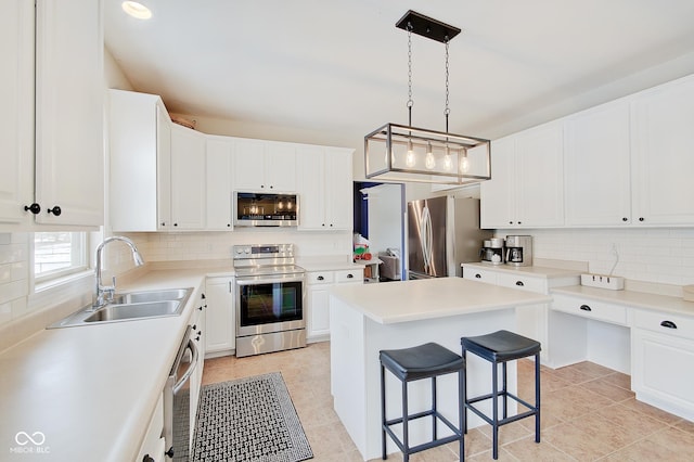 kitchen featuring appliances with stainless steel finishes, a center island, decorative light fixtures, white cabinetry, and sink