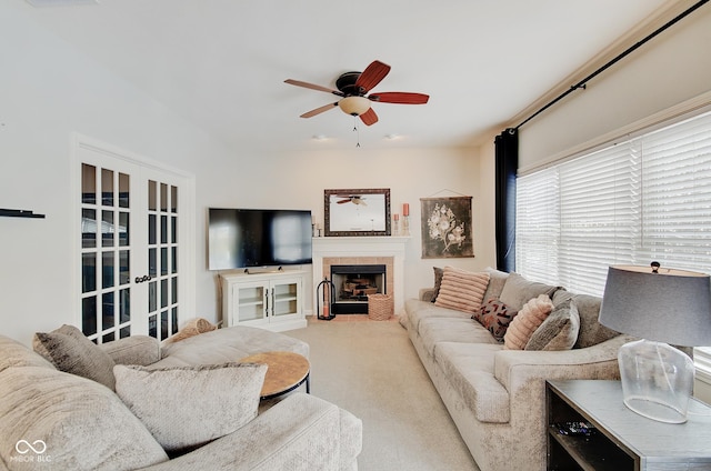 carpeted living room with a fireplace, ceiling fan, and french doors