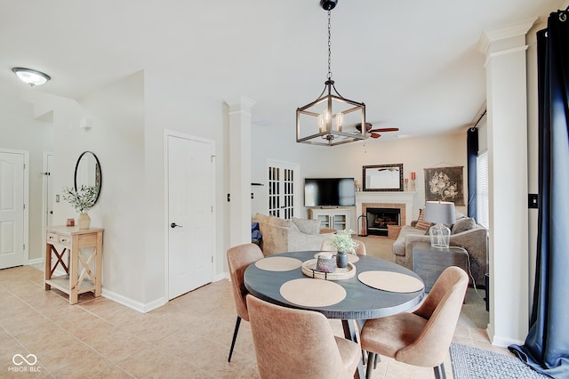 dining area with ceiling fan with notable chandelier, light tile patterned flooring, and a fireplace