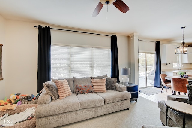 living room featuring light colored carpet and ceiling fan with notable chandelier