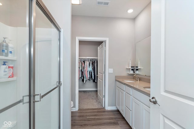 bathroom with a shower with shower door, hardwood / wood-style flooring, vanity, and toilet