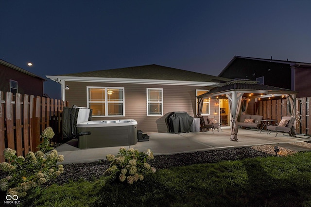 back house at twilight featuring an outdoor living space, a patio area, a gazebo, and a hot tub