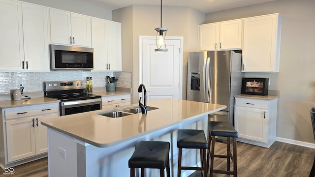 kitchen featuring appliances with stainless steel finishes, sink, white cabinetry, and pendant lighting