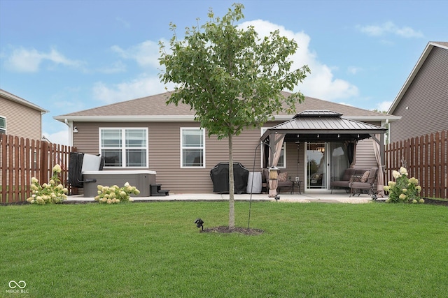 back of property featuring a patio area, a gazebo, a yard, and a hot tub