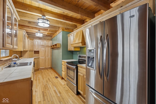 kitchen featuring tile countertops, custom exhaust hood, appliances with stainless steel finishes, beam ceiling, and sink