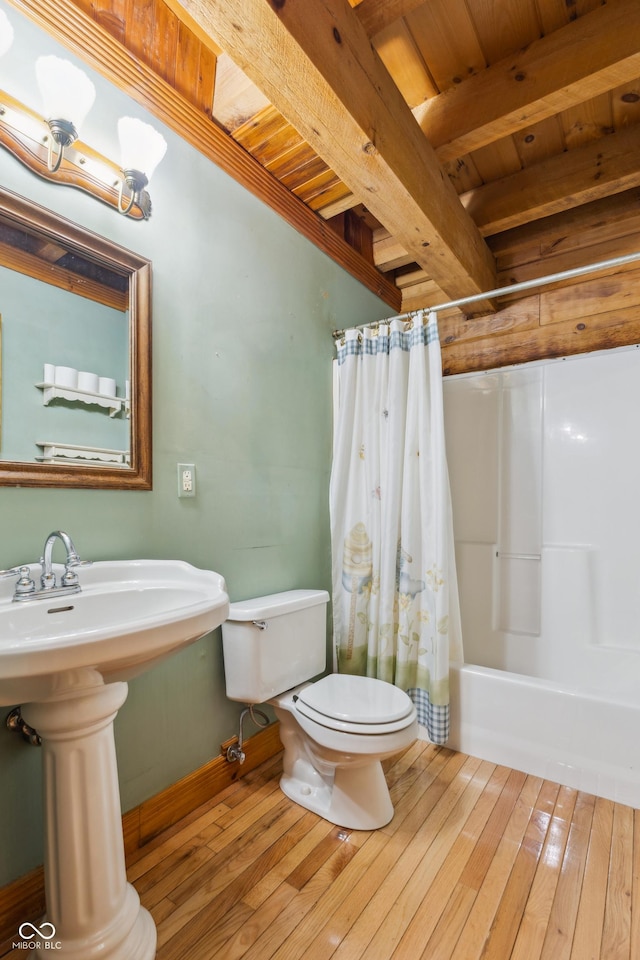 full bathroom with hardwood / wood-style flooring, wooden ceiling, shower / bath combo with shower curtain, beam ceiling, and sink