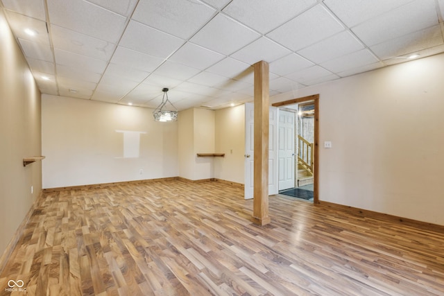 basement with a drop ceiling and light hardwood / wood-style flooring