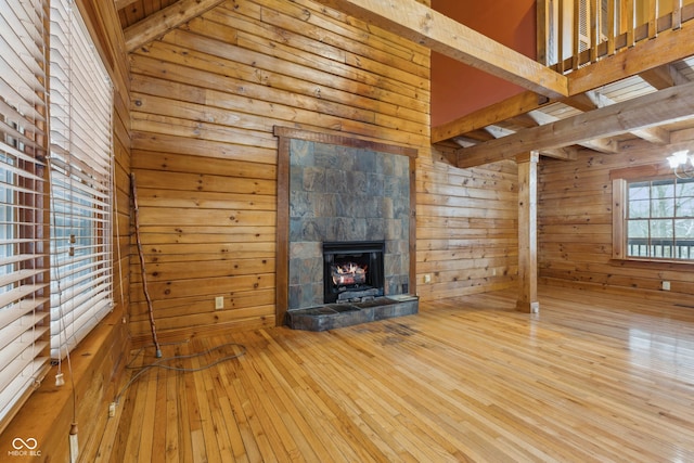 unfurnished living room featuring a high ceiling, a fireplace, wooden walls, and hardwood / wood-style flooring