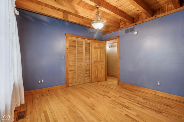 unfurnished bedroom with beam ceiling, light wood-type flooring, and wood ceiling