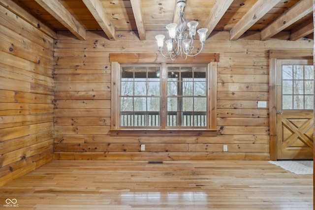 unfurnished dining area featuring wooden ceiling, beamed ceiling, and wooden walls