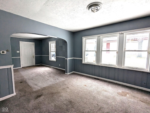 spare room with a textured ceiling and dark colored carpet