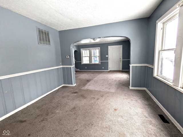 empty room featuring dark carpet and a textured ceiling