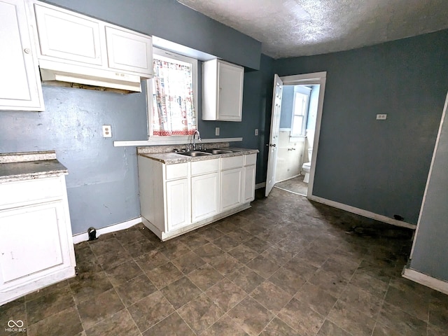 kitchen featuring sink, white cabinetry, and a textured ceiling