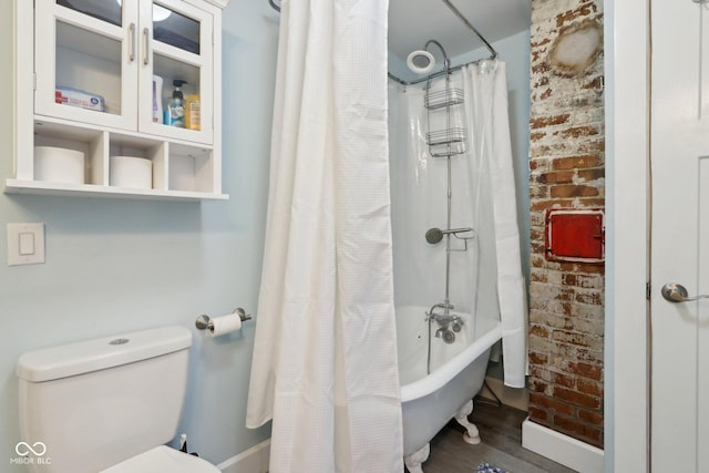 bathroom featuring toilet, shower / tub combo, brick wall, and hardwood / wood-style flooring