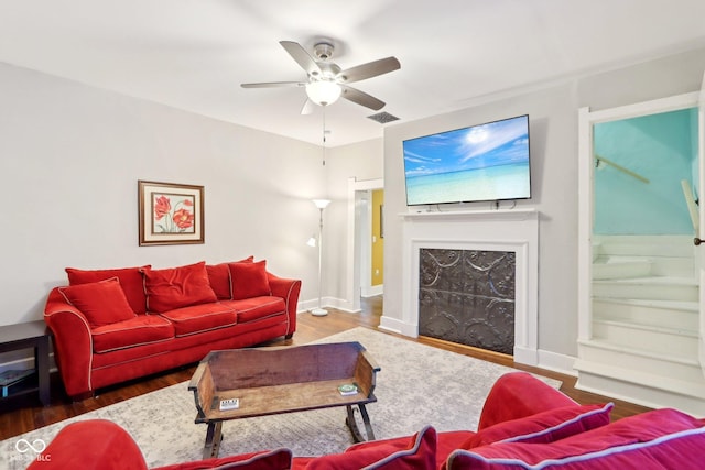 living room with ceiling fan, a high end fireplace, and dark hardwood / wood-style floors