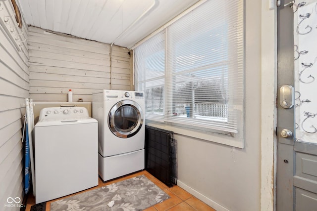 laundry area featuring wood walls, light tile patterned floors, and washing machine and clothes dryer