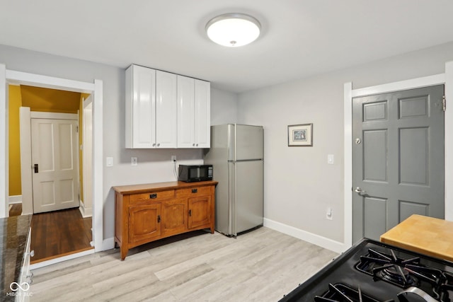 kitchen featuring light wood-type flooring, white cabinets, and black appliances