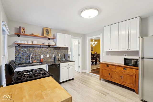 kitchen with wood counters, light hardwood / wood-style floors, white cabinets, and black appliances