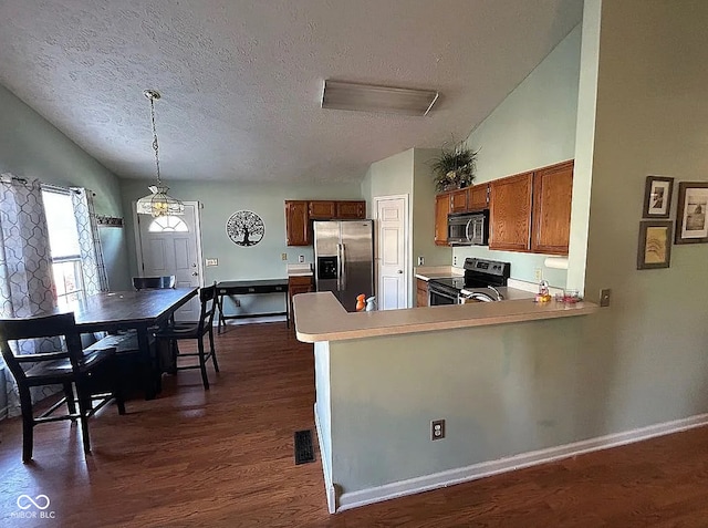 kitchen with a textured ceiling, stainless steel appliances, pendant lighting, and kitchen peninsula