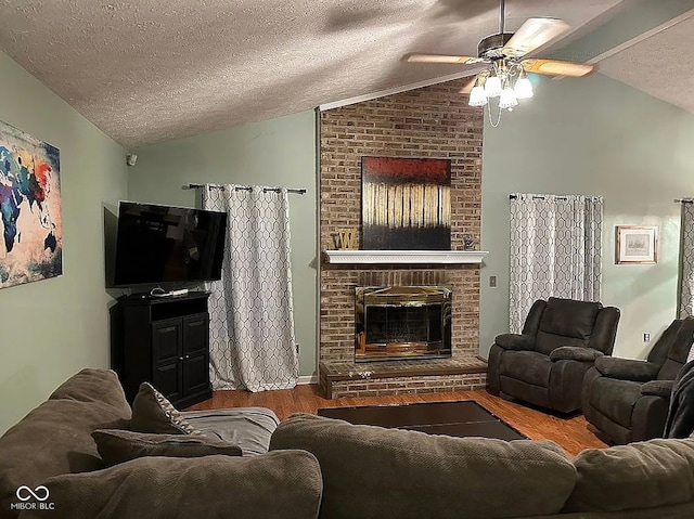 living room featuring hardwood / wood-style floors, a brick fireplace, ceiling fan, a textured ceiling, and vaulted ceiling