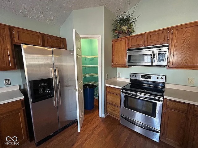 kitchen with dark wood-type flooring, stainless steel appliances, and a textured ceiling