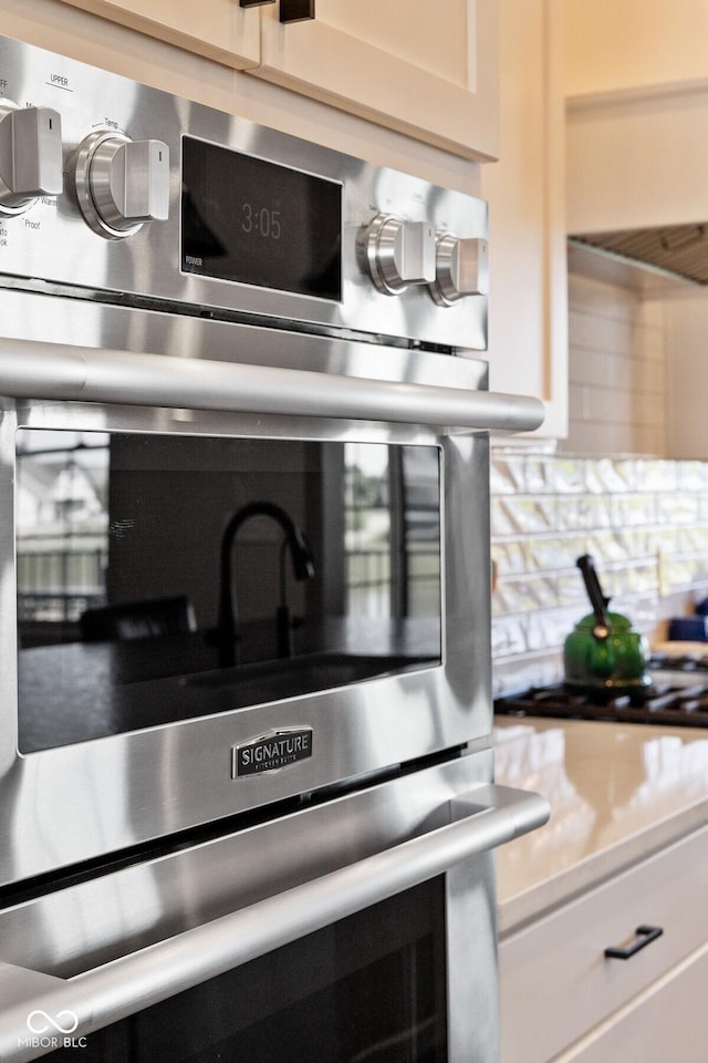 interior details featuring light countertops, stainless steel oven, and white cabinetry