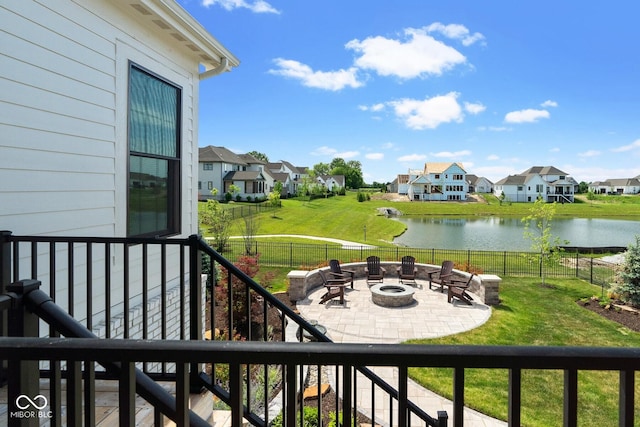 balcony with a water view, a patio area, an outdoor fire pit, and a residential view