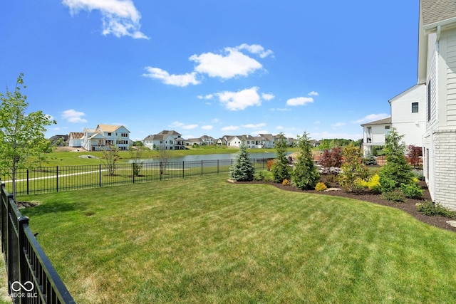 view of yard featuring a water view, a fenced backyard, and a residential view