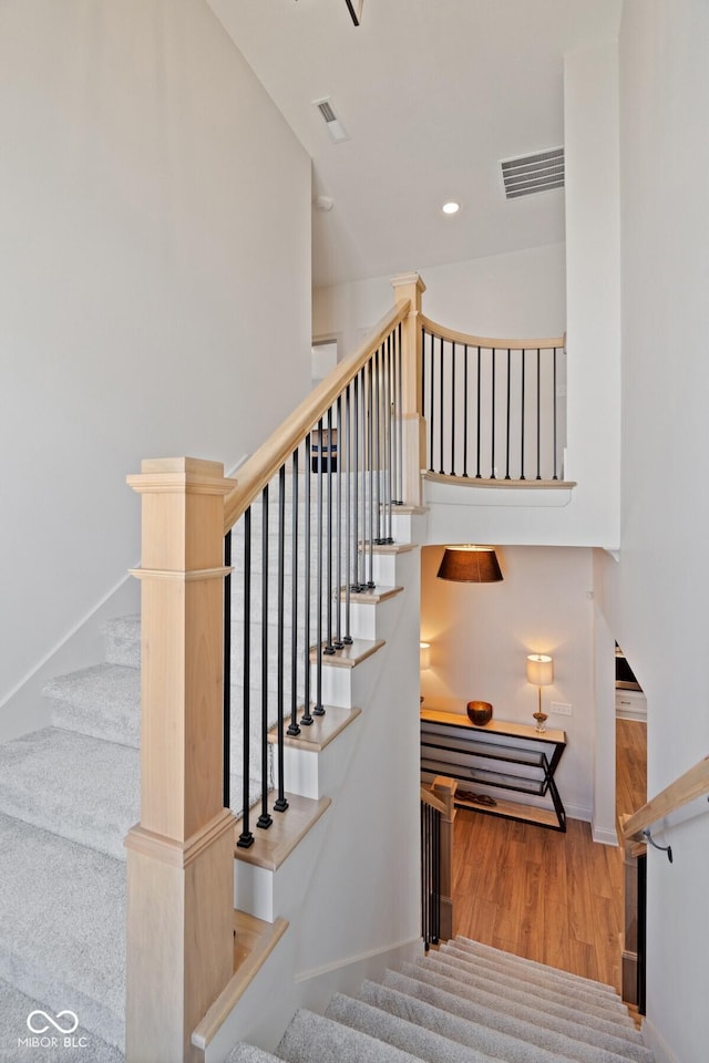 stairway with recessed lighting, wood finished floors, visible vents, and baseboards