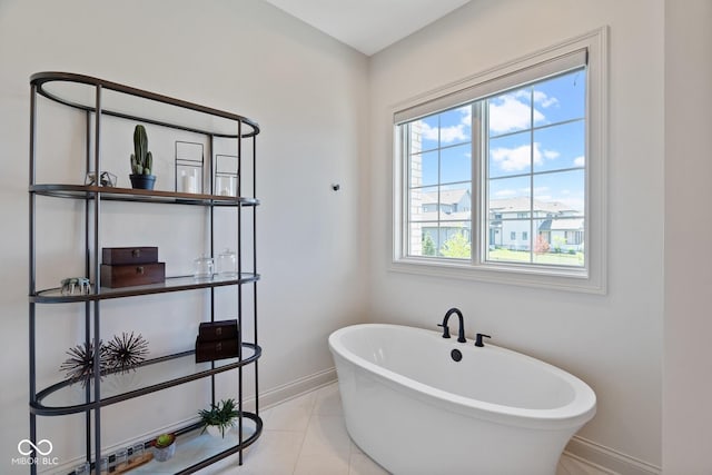 full bath featuring tile patterned flooring, a freestanding tub, and baseboards