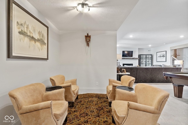 carpeted living room featuring a fireplace, baseboards, a textured ceiling, and recessed lighting