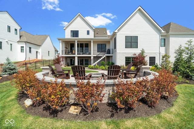 rear view of property with brick siding, an outdoor fire pit, fence, and a balcony