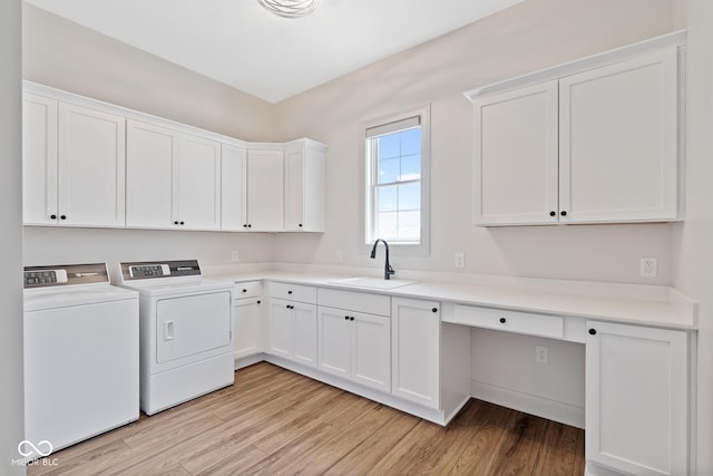 laundry area with a sink, light wood finished floors, washing machine and dryer, and cabinet space