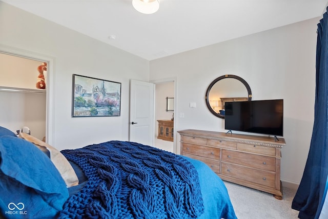 bedroom featuring light carpet and a walk in closet