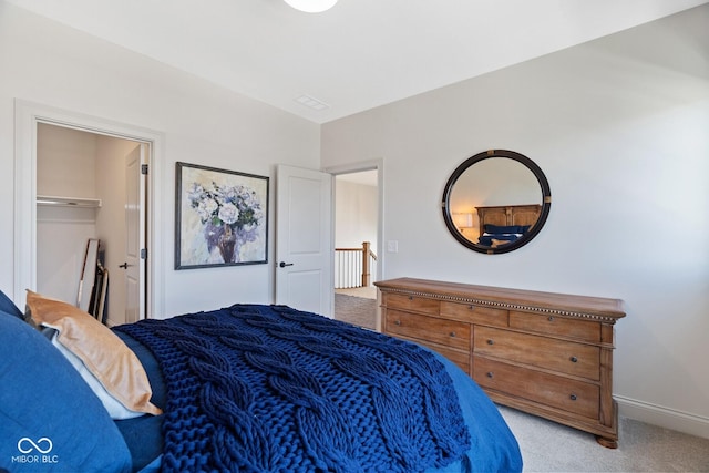 bedroom featuring light carpet, baseboards, and a walk in closet