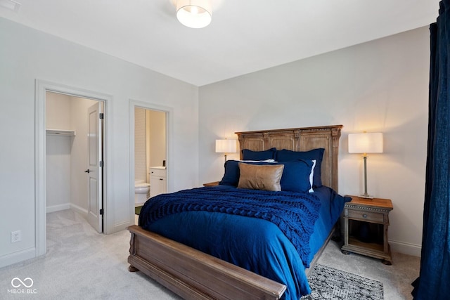 bedroom featuring light colored carpet, ensuite bath, and baseboards