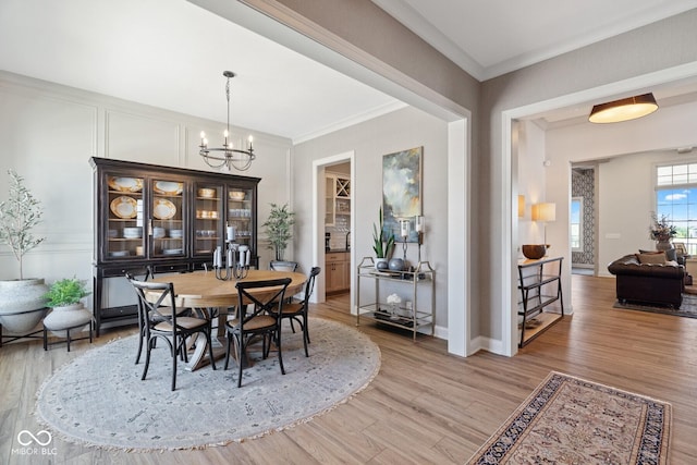 dining room featuring a chandelier, baseboards, wood finished floors, and crown molding