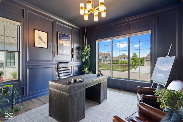 office space with crown molding, an inviting chandelier, light wood-style flooring, and a decorative wall