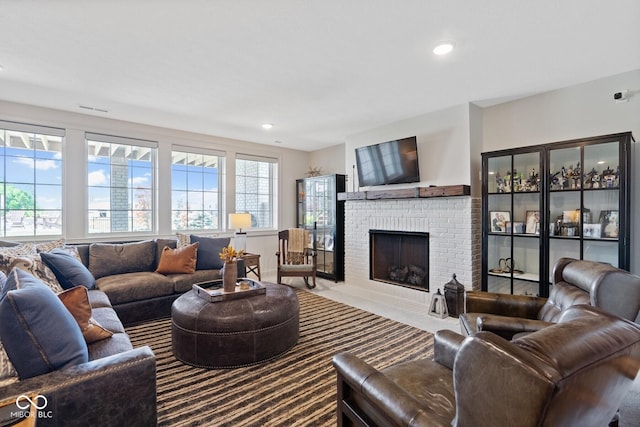 carpeted living area featuring a brick fireplace, visible vents, and recessed lighting