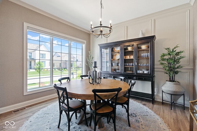 dining space featuring an inviting chandelier, baseboards, visible vents, and wood finished floors