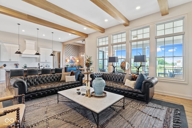 living room with baseboards, plenty of natural light, beam ceiling, and light wood-style floors