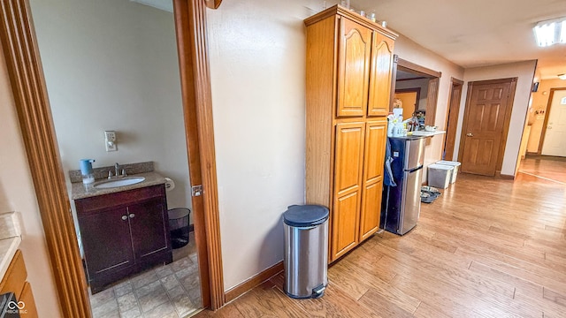 hallway with sink and light hardwood / wood-style flooring