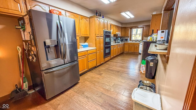 kitchen with sink, appliances with stainless steel finishes, and light hardwood / wood-style flooring